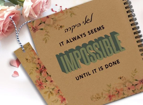 מחברת מעוצבת עם שם ומשפט השראה: ״It always seems impossible until it's done״