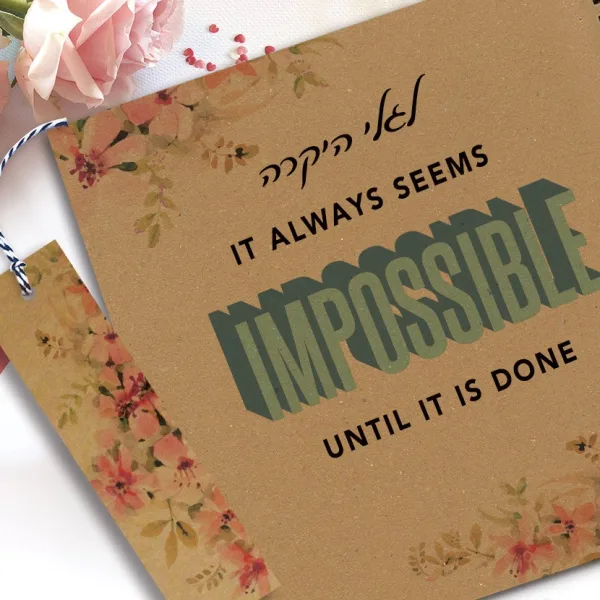 מחברת מעוצבת עם שם ומשפט השראה: ״It always seems impossible until it's done״