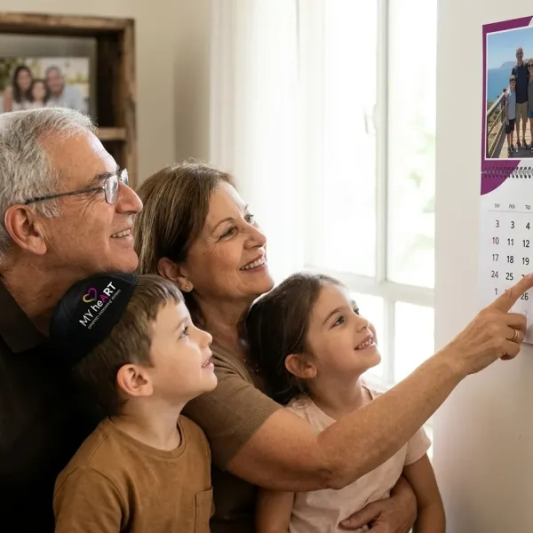 משפחה (סבא, סבתא, נכדים) מסתכלת יחד בחיוך על לוח שנה מעוצב עם תמונותיהם תלוי על הקיר.